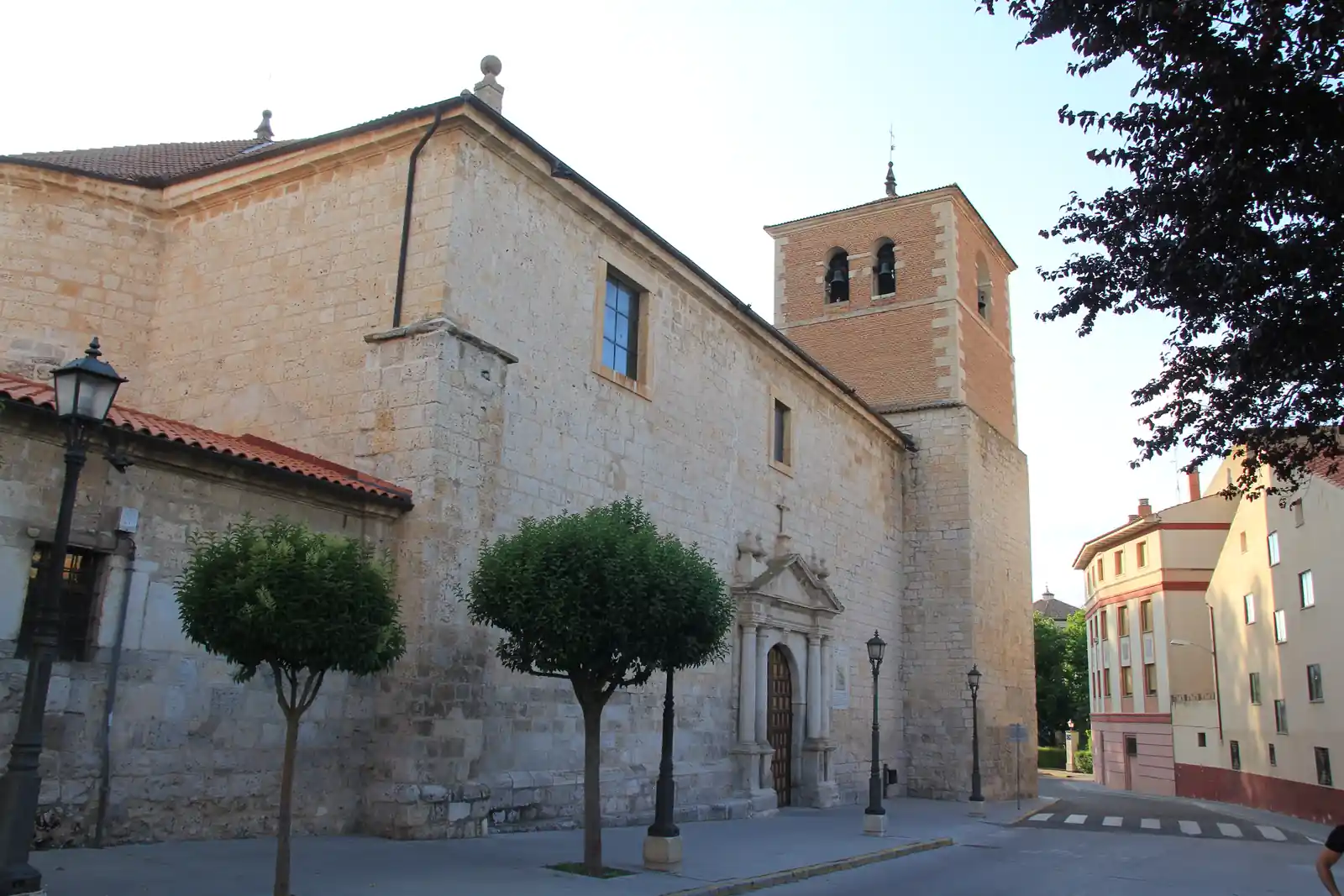 Exterior de la iglesia de San Miguel de Reoyo con portada de piedra y campanario de ladrillo